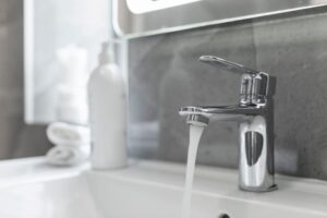 Selective,Focus,In,Water,Flowing,From,Tap,In,Bathroom,With